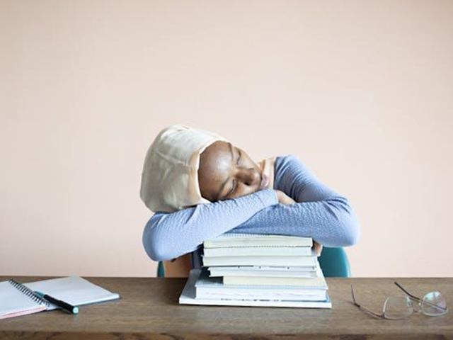 A girl resting her head on top of books